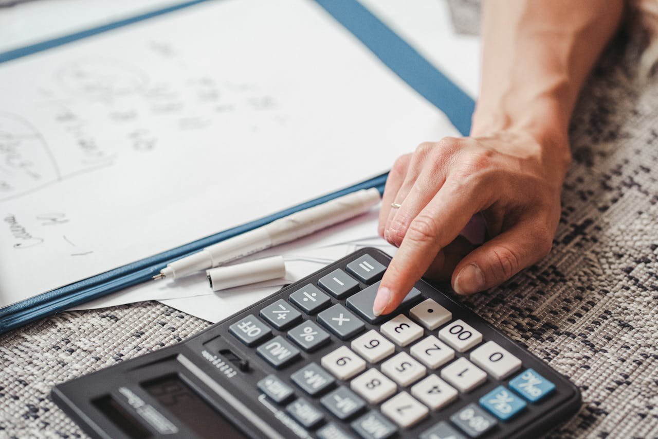 A hand using a calculator on top of documents, indicating financial calculation or analysis.